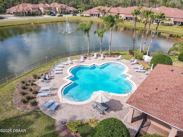 community pool with a patio area, a water view, and fence