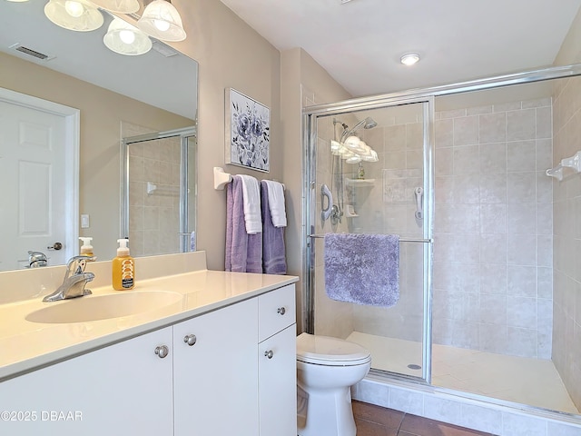 bathroom featuring visible vents, vanity, toilet, and a shower stall