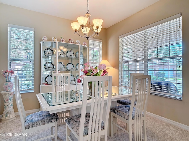 carpeted dining space featuring an inviting chandelier and baseboards