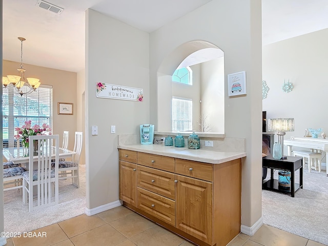 kitchen with an inviting chandelier, light colored carpet, hanging light fixtures, and a wealth of natural light