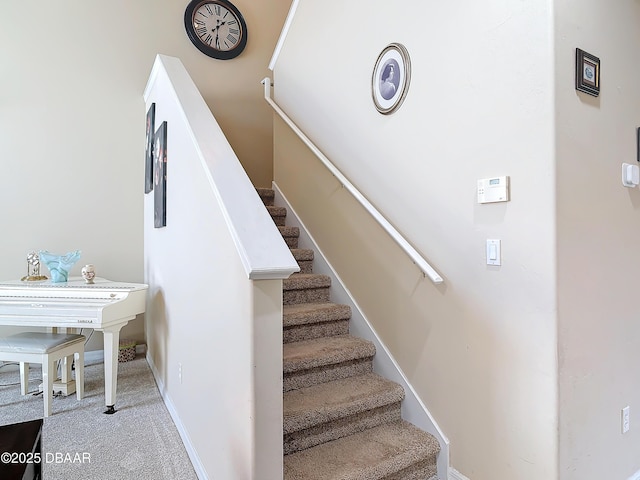 staircase featuring baseboards and carpet