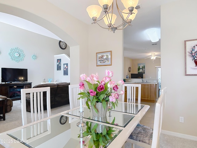 dining area featuring visible vents, ceiling fan with notable chandelier, arched walkways, baseboards, and light colored carpet