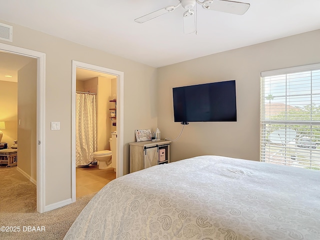 bedroom with light carpet, connected bathroom, a ceiling fan, and baseboards