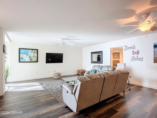 living room featuring dark wood-type flooring and ceiling fan