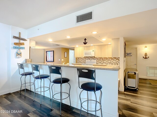 kitchen with dark hardwood / wood-style flooring, white cabinets, kitchen peninsula, light stone countertops, and white appliances