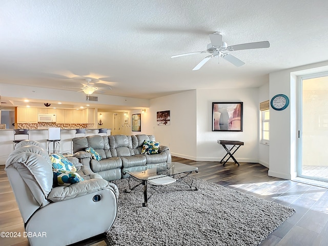 living room featuring a textured ceiling, hardwood / wood-style flooring, and ceiling fan