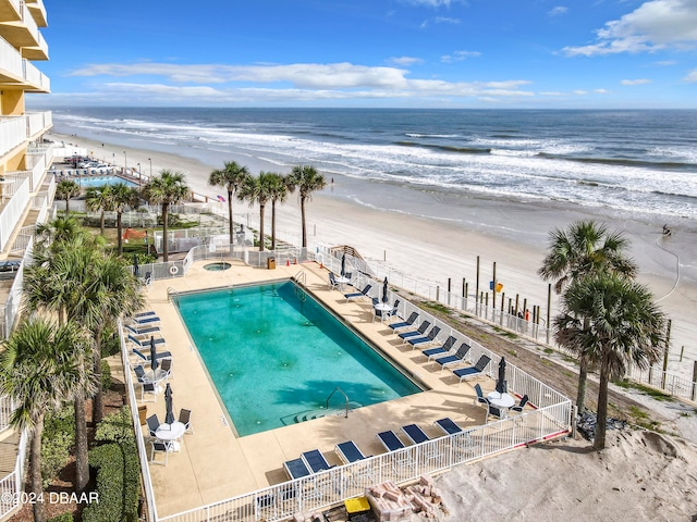 view of pool featuring a patio, a beach view, and a water view