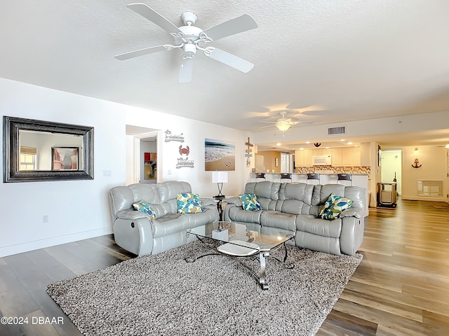 living room featuring hardwood / wood-style floors, ceiling fan, and a textured ceiling