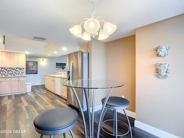 kitchen featuring stainless steel fridge, dark hardwood / wood-style flooring, hanging light fixtures, decorative backsplash, and a chandelier