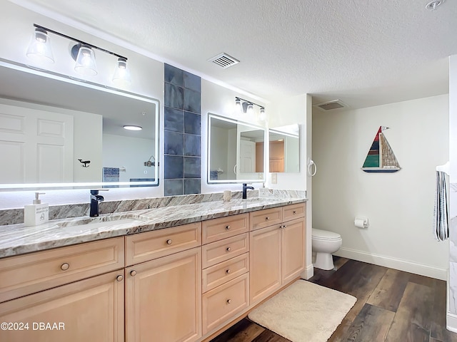 bathroom with hardwood / wood-style floors, vanity, a textured ceiling, and toilet