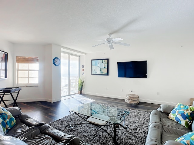 living room with dark hardwood / wood-style flooring, a textured ceiling, and ceiling fan