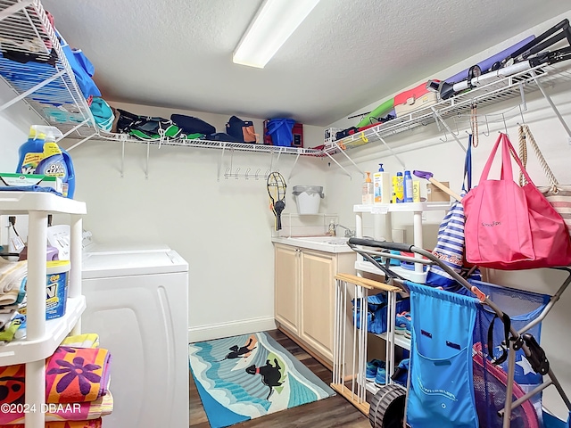 washroom with wood-type flooring, cabinets, a textured ceiling, sink, and washing machine and clothes dryer