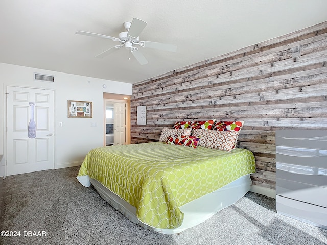 bedroom with wooden walls, carpet flooring, and ceiling fan