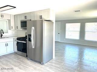 124 Harrison Rd, Daytona Beach, FL 32118 - kitchen featuring a sink, light countertops, light wood-style flooring, and appliances with stainless steel finishes