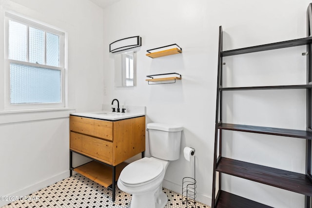 bathroom with baseboards, vanity, and toilet