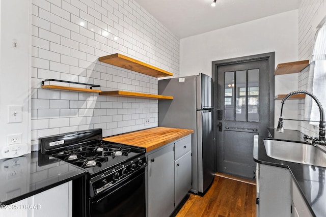 kitchen featuring a sink, decorative backsplash, dark wood-style floors, open shelves, and gas stove