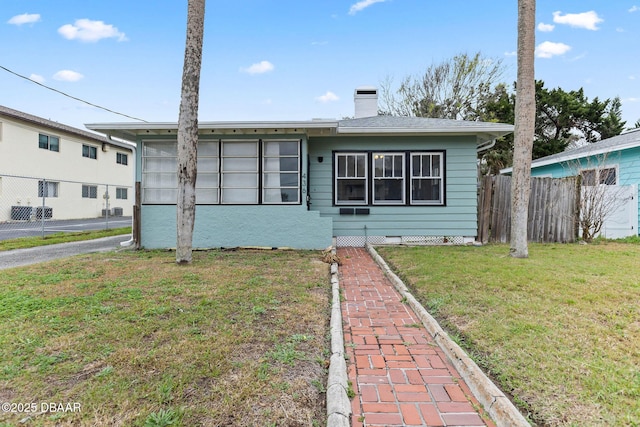 view of front of home with a chimney, a front yard, and fence