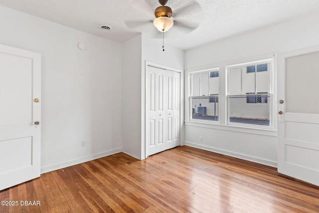 unfurnished bedroom featuring a closet, visible vents, light wood-style flooring, a textured ceiling, and baseboards