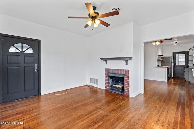 unfurnished living room featuring baseboards, visible vents, ceiling fan, wood finished floors, and a fireplace