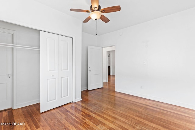 unfurnished bedroom with a ceiling fan, a closet, baseboards, and wood finished floors