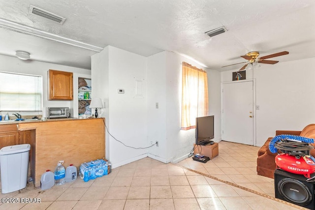 kitchen with a textured ceiling, light tile patterned flooring, a sink, and visible vents
