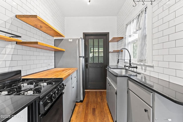 kitchen with dark wood-type flooring, gas stove, a sink, and open shelves