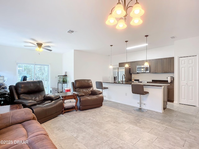 living room featuring visible vents and ceiling fan with notable chandelier