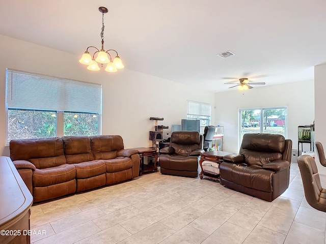 living room featuring light tile patterned floors, visible vents, a wealth of natural light, and ceiling fan with notable chandelier