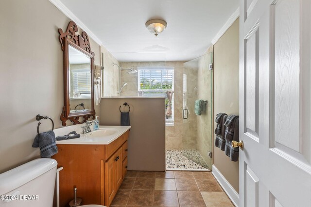 bathroom featuring vanity, tile patterned flooring, toilet, ornamental molding, and a shower with shower door