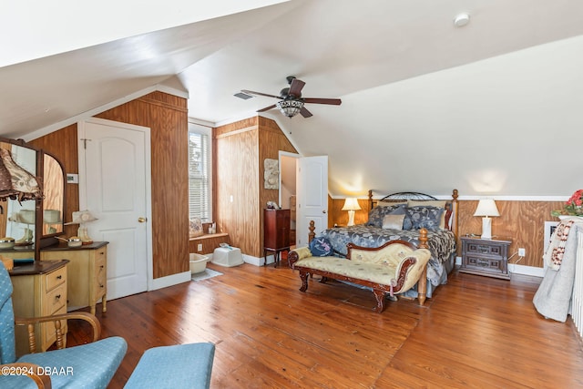 bedroom featuring wood-type flooring, vaulted ceiling, ceiling fan, and wooden walls