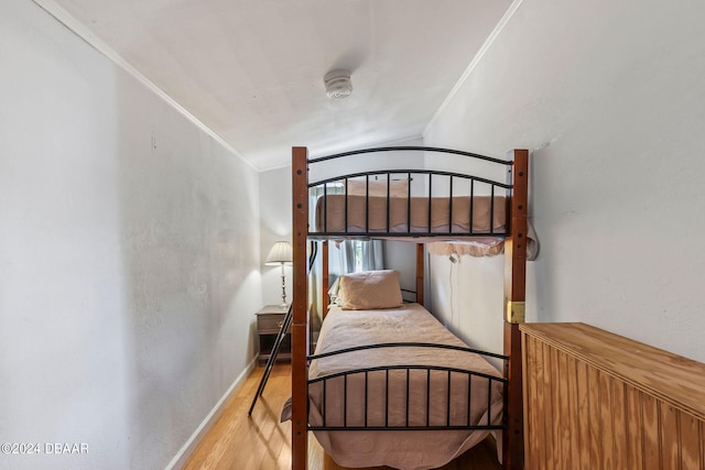 bedroom featuring vaulted ceiling, ornamental molding, and light hardwood / wood-style flooring