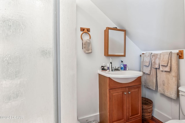 bathroom featuring vanity, toilet, walk in shower, and lofted ceiling