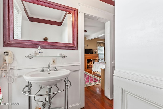 bathroom with hardwood / wood-style floors, ornamental molding, sink, and beamed ceiling