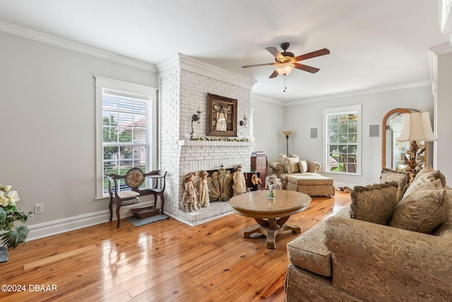 living room with a fireplace, hardwood / wood-style floors, ornamental molding, and a healthy amount of sunlight