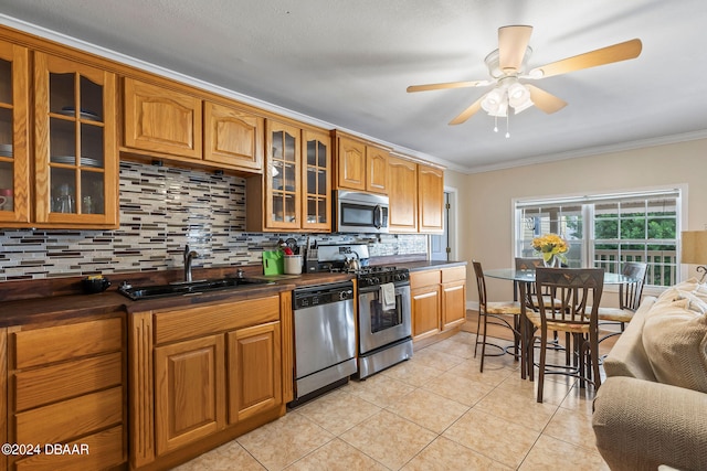 kitchen with sink, stainless steel appliances, backsplash, light tile patterned flooring, and ornamental molding