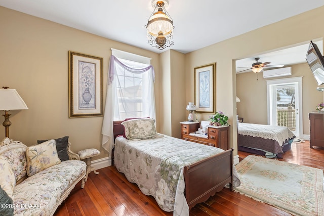 bedroom with ceiling fan with notable chandelier, dark hardwood / wood-style floors, and an AC wall unit