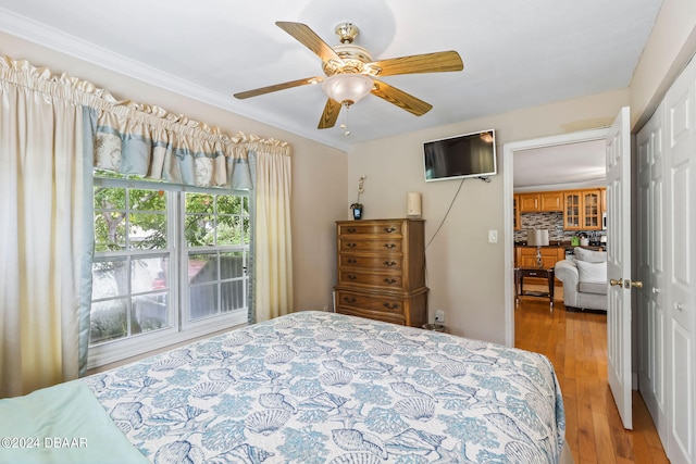 bedroom with ceiling fan, a closet, ornamental molding, and light hardwood / wood-style flooring