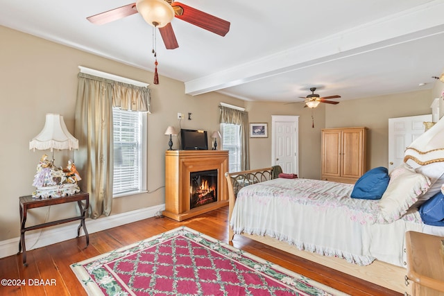 bedroom with hardwood / wood-style floors, ceiling fan, and beam ceiling