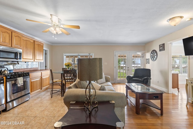 living room featuring ceiling fan, light wood-type flooring, ornamental molding, and french doors