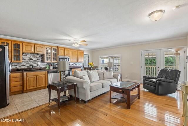 living room featuring ceiling fan, light hardwood / wood-style floors, sink, and crown molding