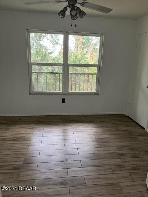 spare room with ceiling fan, wood-type flooring, and a healthy amount of sunlight