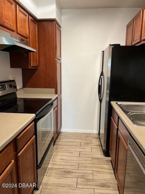 kitchen with extractor fan, appliances with stainless steel finishes, and light hardwood / wood-style flooring