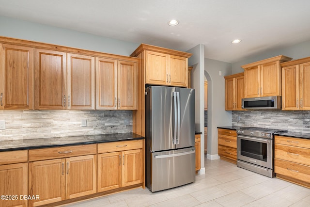 kitchen featuring tasteful backsplash, dark stone counters, and appliances with stainless steel finishes