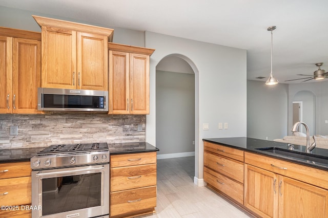 kitchen with appliances with stainless steel finishes, pendant lighting, sink, decorative backsplash, and ceiling fan