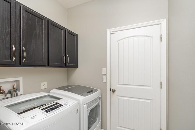 washroom featuring cabinets and washer and clothes dryer