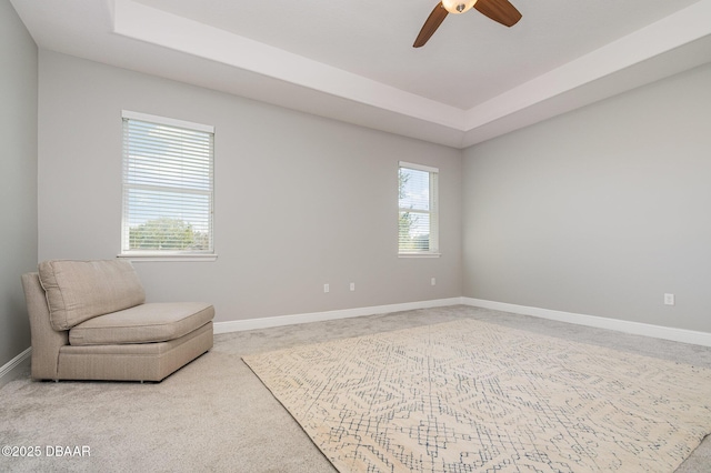 sitting room with light colored carpet, a raised ceiling, and a healthy amount of sunlight