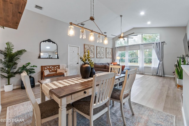 dining area with high vaulted ceiling, visible vents, ceiling fan, and light wood-style flooring