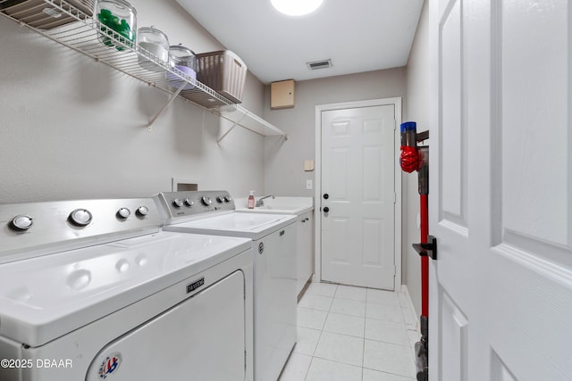 laundry room with light tile patterned floors, washing machine and dryer, laundry area, a sink, and visible vents