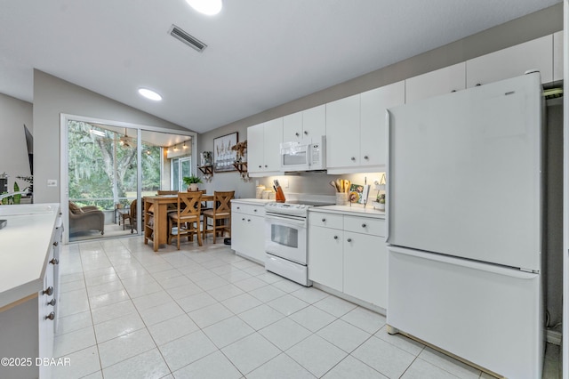 kitchen featuring white appliances, visible vents, vaulted ceiling, light countertops, and light tile patterned flooring