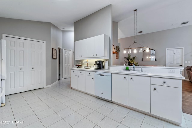 kitchen featuring white appliances, light countertops, a sink, and a peninsula